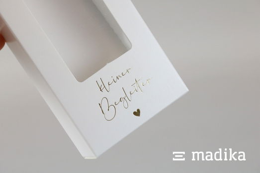 Diese weiße Faltschachtel ist schlicht, sticht aber dank Sichtfenster und Heißfolienprägung als besonders hochwertig hervor. Weiße Faltschachtel mit Sichtfenster und Heißfolie