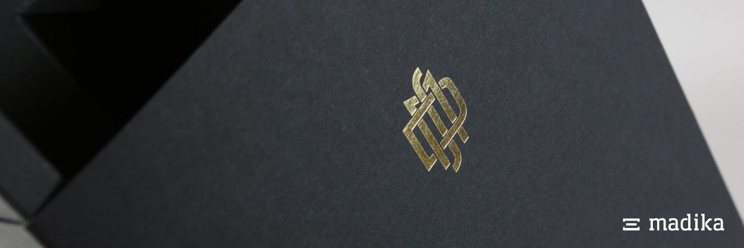 Schwarze Naturkarton-Schachtel mit zierlicher goldener Veredelung. Schwarze Naturkartonschachtel mit goldener Veredelung