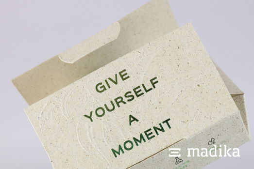 Diese Graskartonverpackung wurde mit verschiedenen Veredelungen verziert. Schachtel aus Graskarton mit einer Heißprägung aus Gold