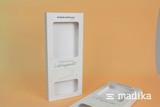 Faltschachtel mit Sichtfenster und minimalistischer Bedruckung. Eine weiße Faltschachtel mit Sichtfenster und minimalistischen Bedruckung